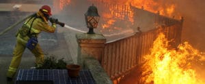 Firefighter dowsing a deck fire